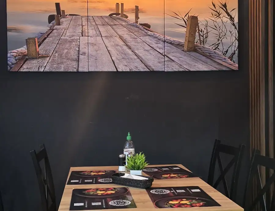 Sala ze stolikami i zdjęciem pomostu nad morzem
