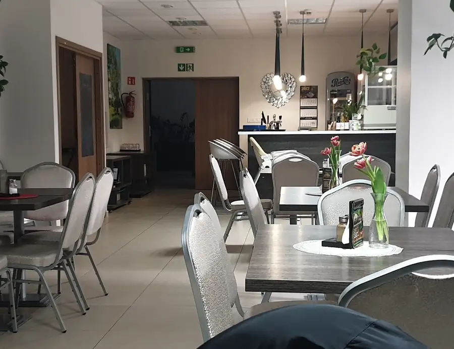 Jasna sala z szarymi krzesłami i kwiatami